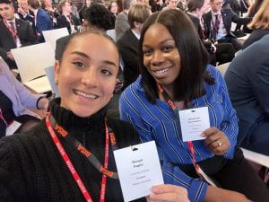 Dunya and Chinumezi smiling at the camera as they hold up their passes for the event.